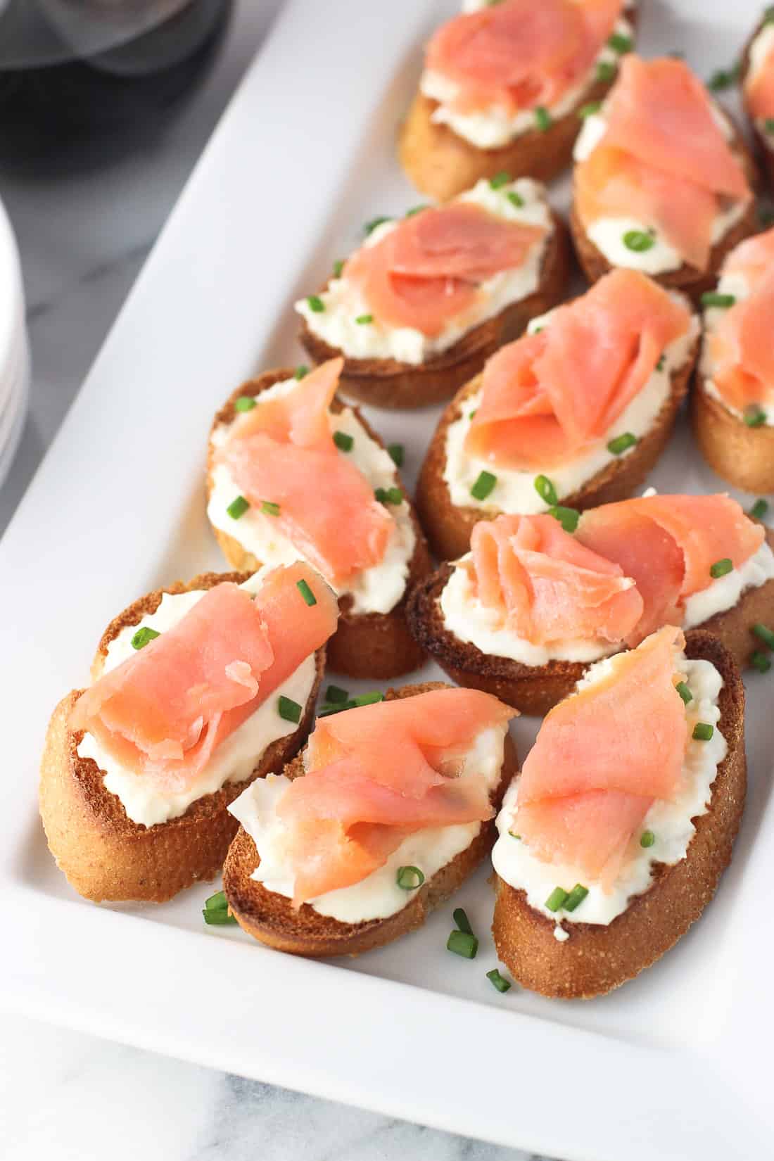 Crostini topped with burrata and a slice of smoked salmon on a tray.