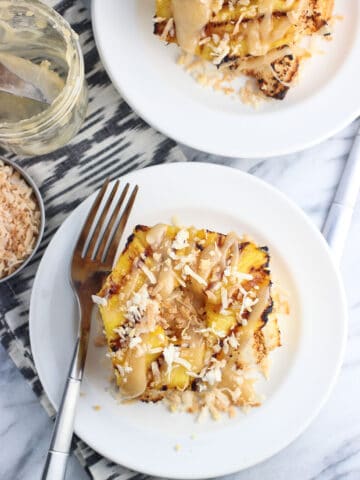 A serving of angel food cake, grilled pineapple, coconut, and caramel sauce on a dessert plate.