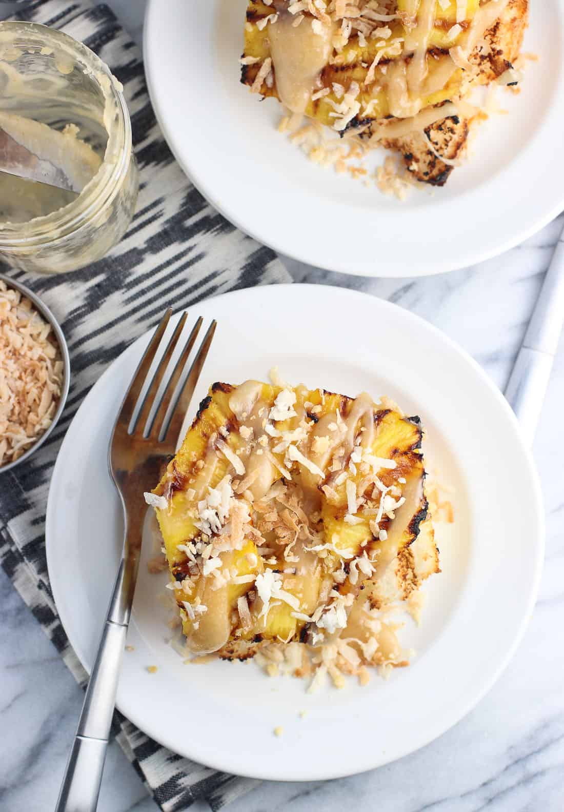 A serving of angel food cake, grilled pineapple, coconut, and caramel sauce on a dessert plate.