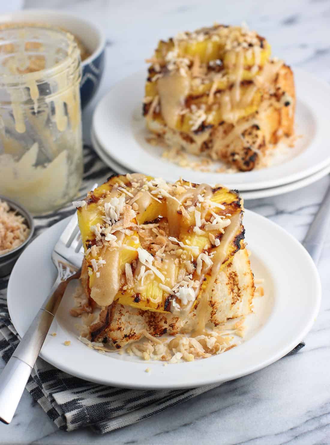 Cake topped with pineapple, coconut, and caramel on plates with a fork.