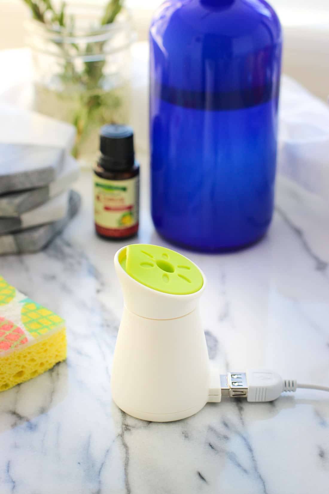 The mini diffuser on a table next to a soap dispenser and a sponge.