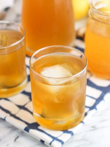 Glasses of iced green tea on a cloth placemat in front of a full carafe of tea