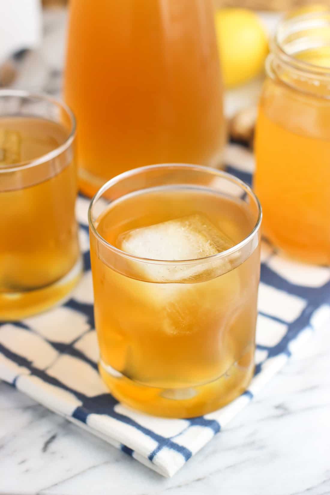 Glasses of iced green tea on a cloth placemat in front of a full carafe of tea