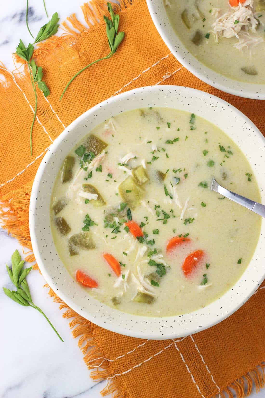 A bowl of coconut curry chicken soup with a spoon in it.