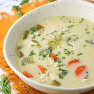 A shallow ceramic bowl of soup on a fringed linen placemat.