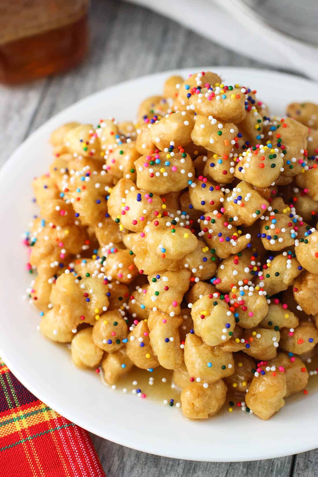 A tall mound of struffoli covered in honey and sprinkles