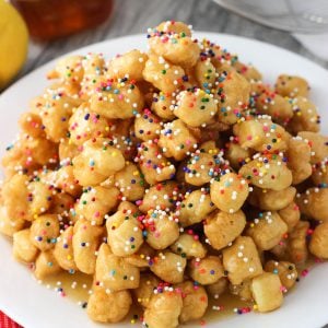Struffoli on a plate covered in honey and rainbow nonpareils