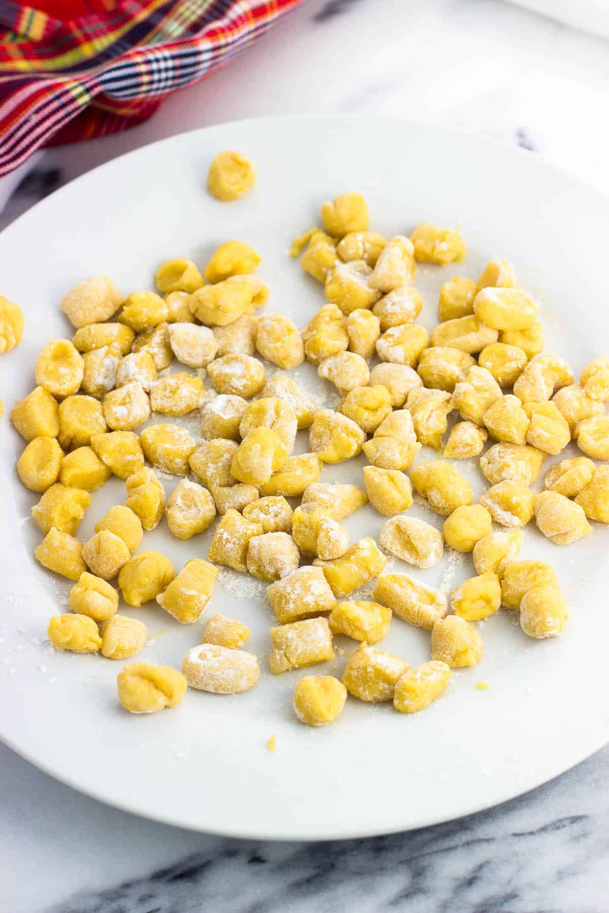 Small balls of dough tossed in flour on a plate before frying