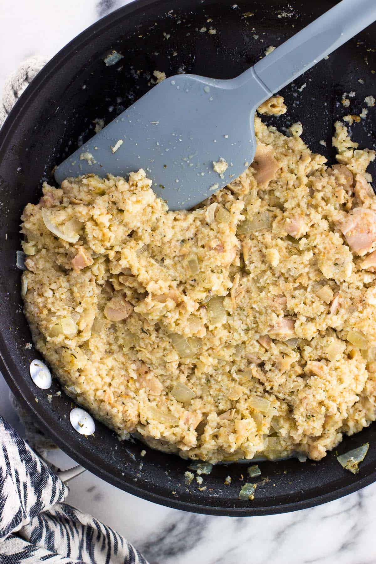 Clam dip mixture in a skillet with a spatula before baking.