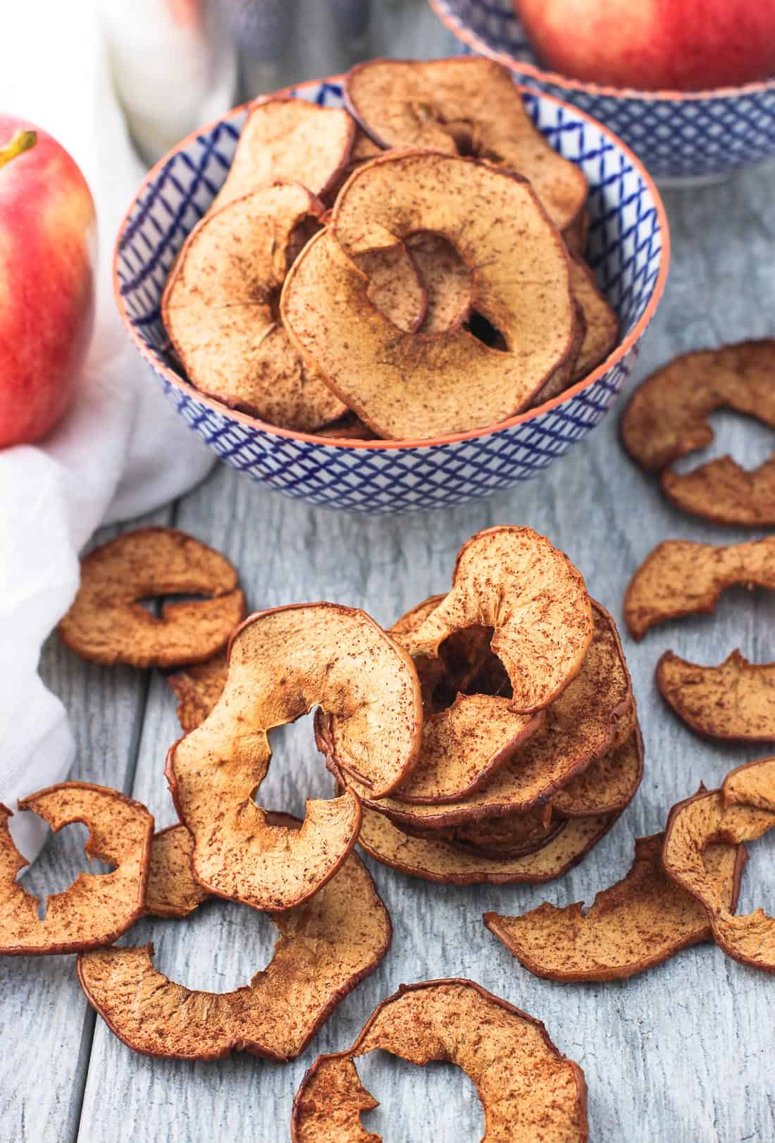 Crisp baked apple chips in a bowl and laid out on a table