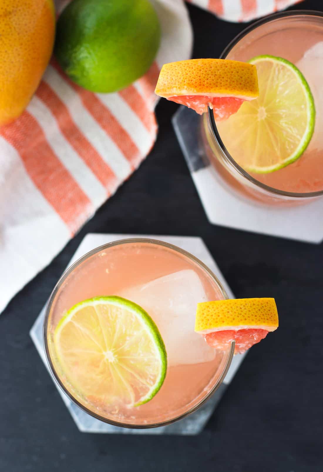 Two palomas in short glasses garnished with a grapefruit wedge and a lime round