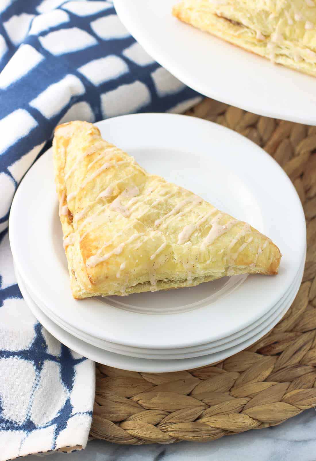 An apple turnover sitting on a stack of dessert plates.