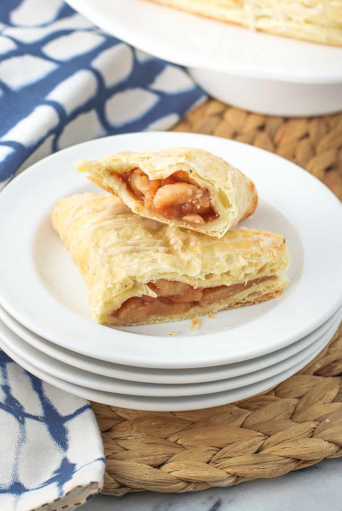 An apple turnover cut in half on a stack of dessert plates.