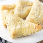 Four apple turnovers on a cake stand.