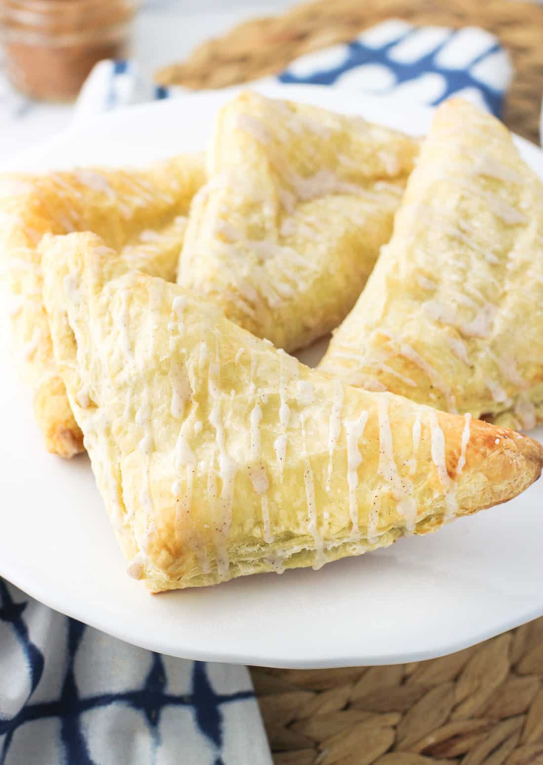 Four apple turnovers on a cake stand.