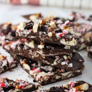 A stack of four peppermint bark pieces on a sheet of parchment, surrounded by other pieces of bark