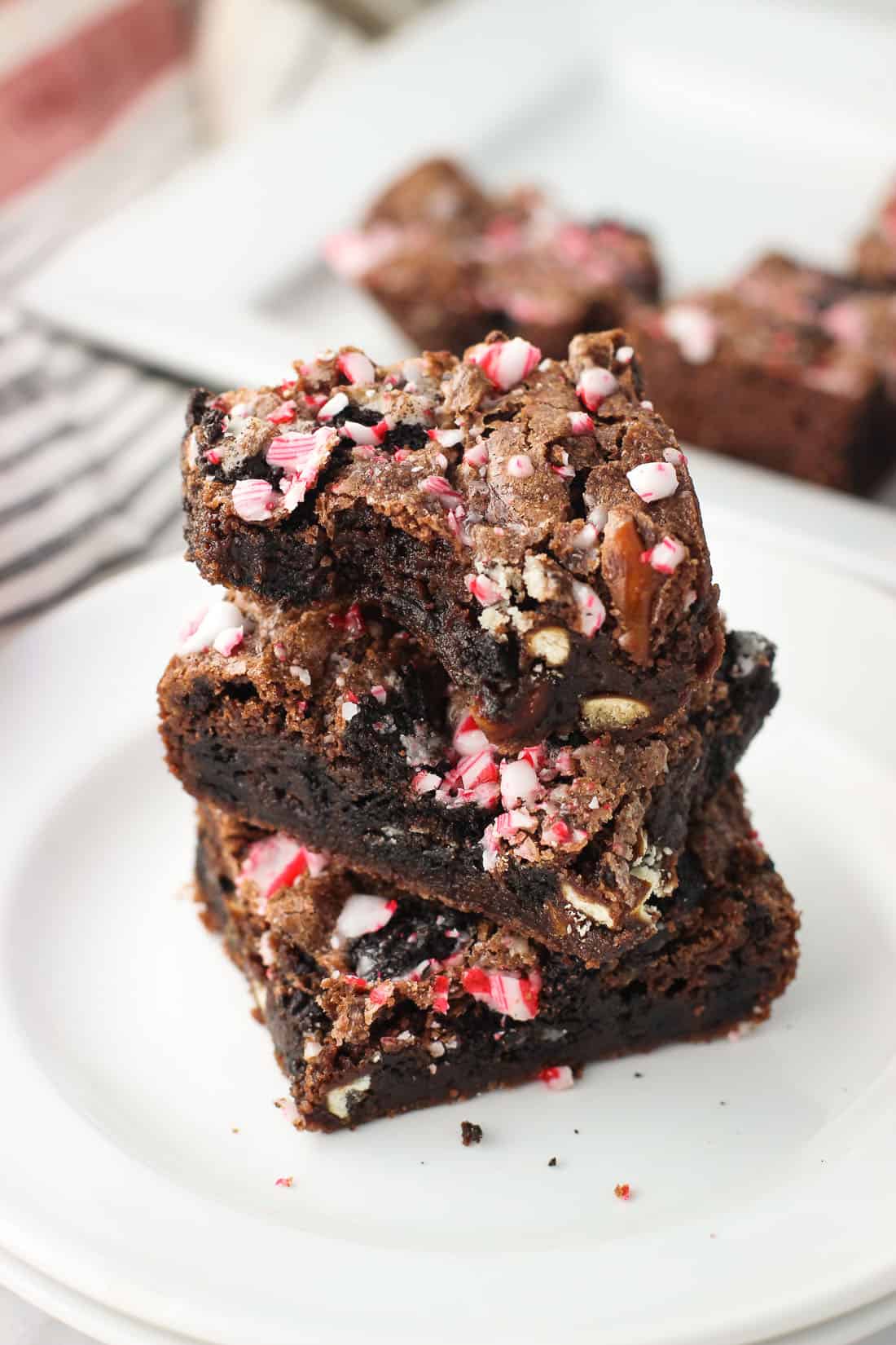 Three brownies stacked on top of one another on a dessert plate, with a bite taken out of the top brownie