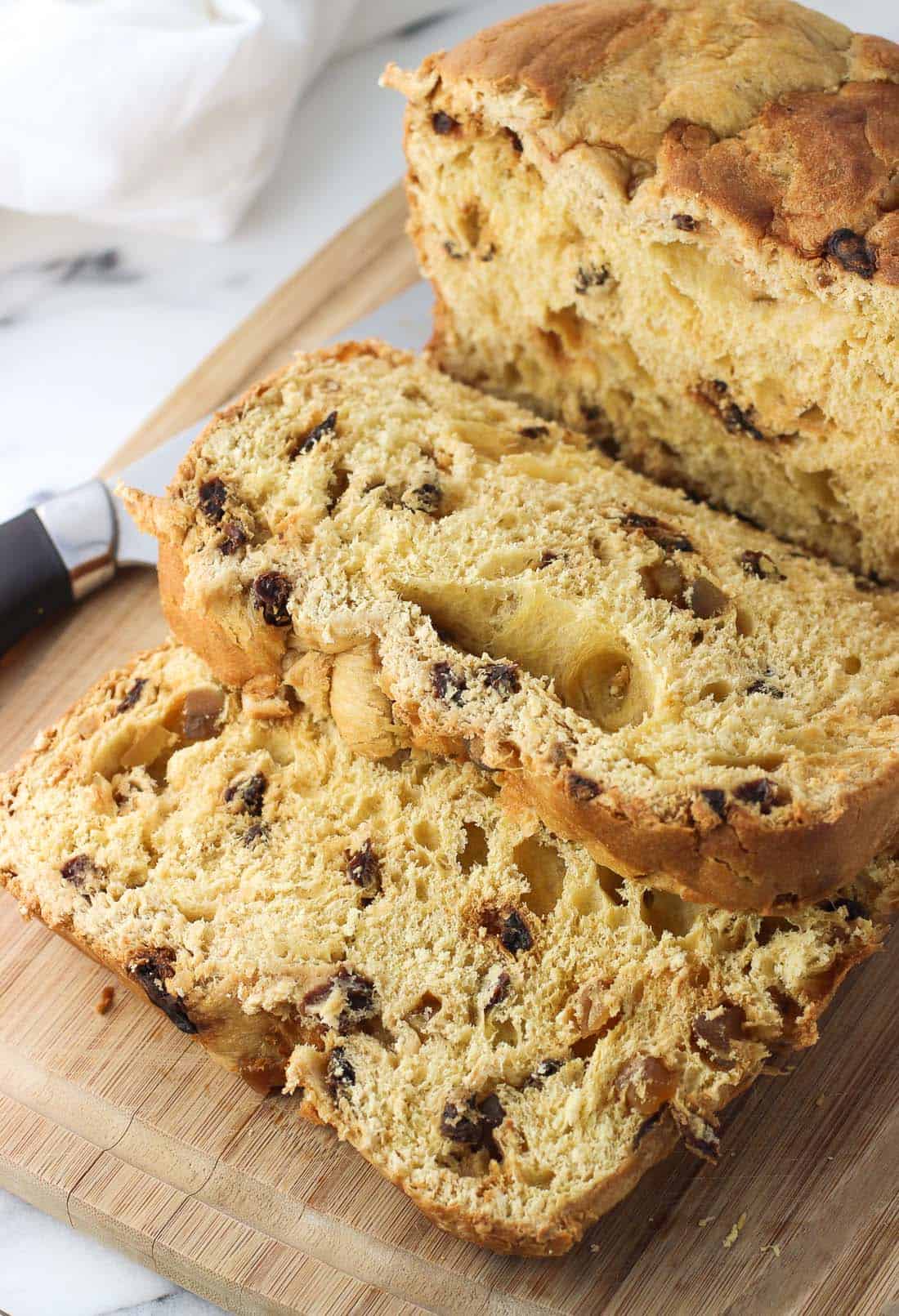 A loaf of panettone cut into slices on a wooden cutting board