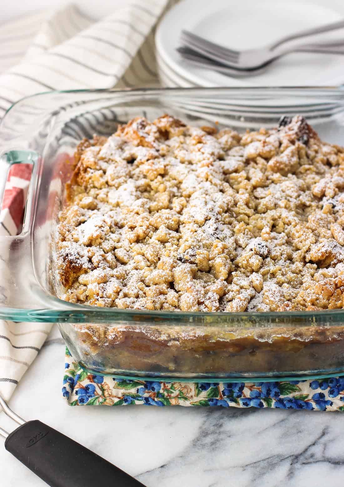 The cooled french toast bake in the baking dish dusted with confectioners' sugar before being sliced