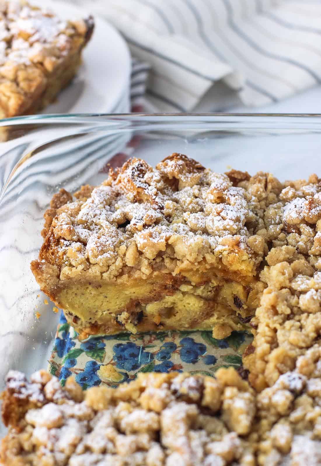 A side view of a slice of this french toast bake in the baking dish once the slice in front of it was removed