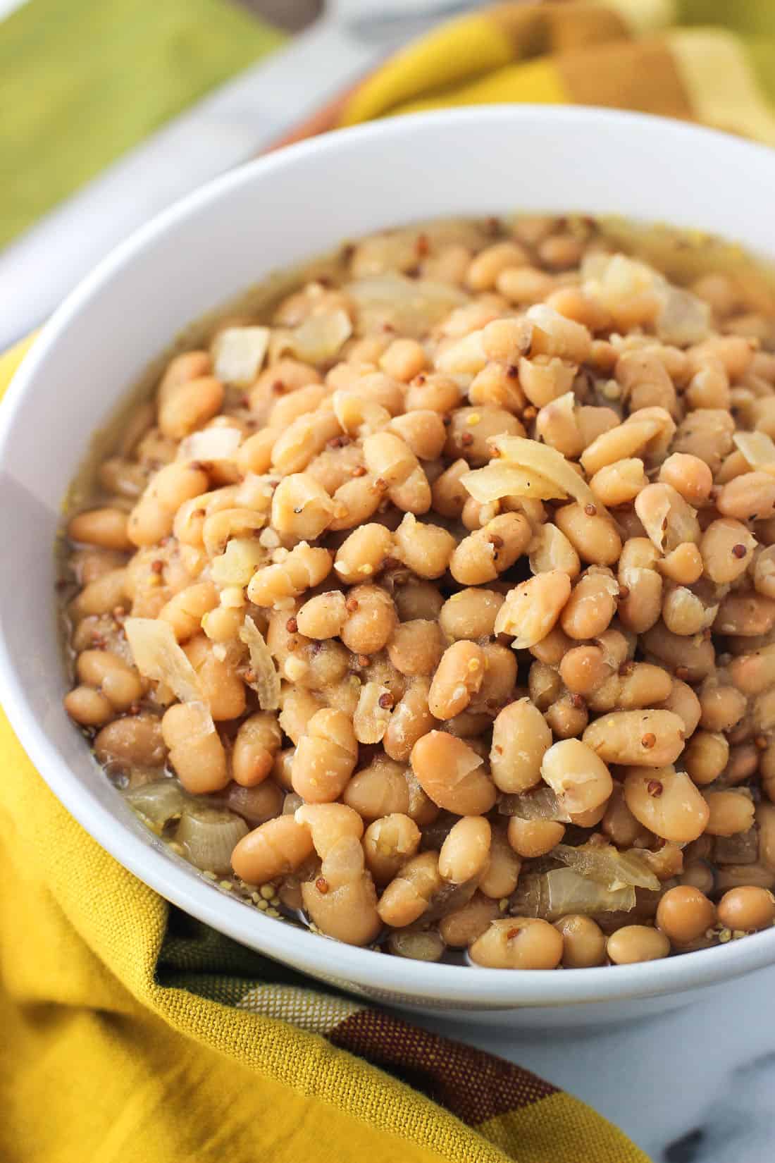 Cannellini beans in a mustard beer sauce in a ceramic bowl