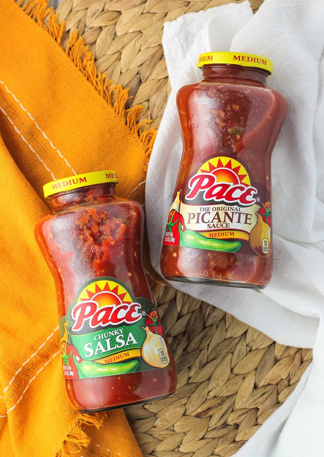 An overhead picture of two jars on a woven placemat - one Pace chunky salsa and the other Pace picante sauce