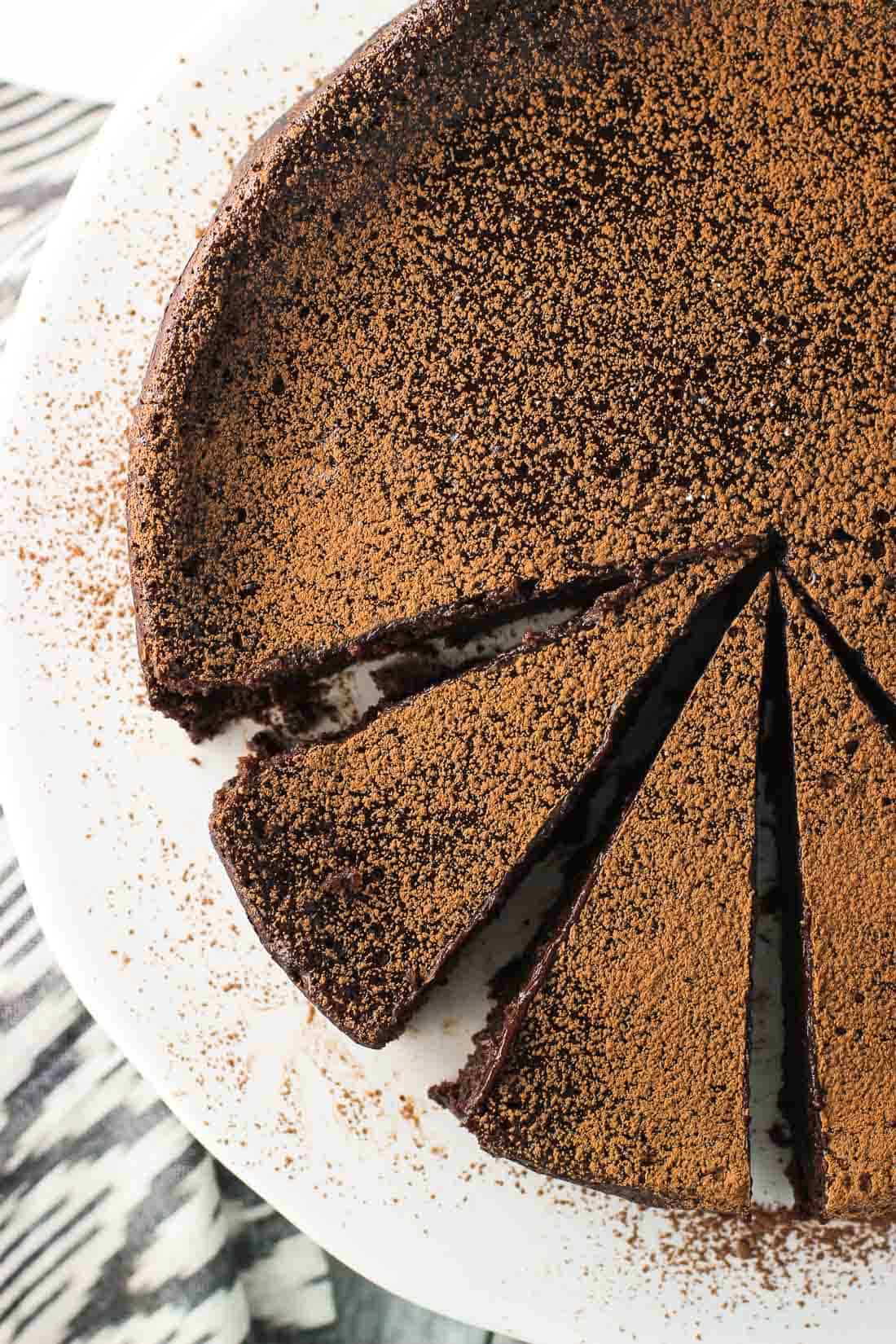 An overhead shot of the cake on a ceramic cake stand, partially sliced into slightly narrow slices