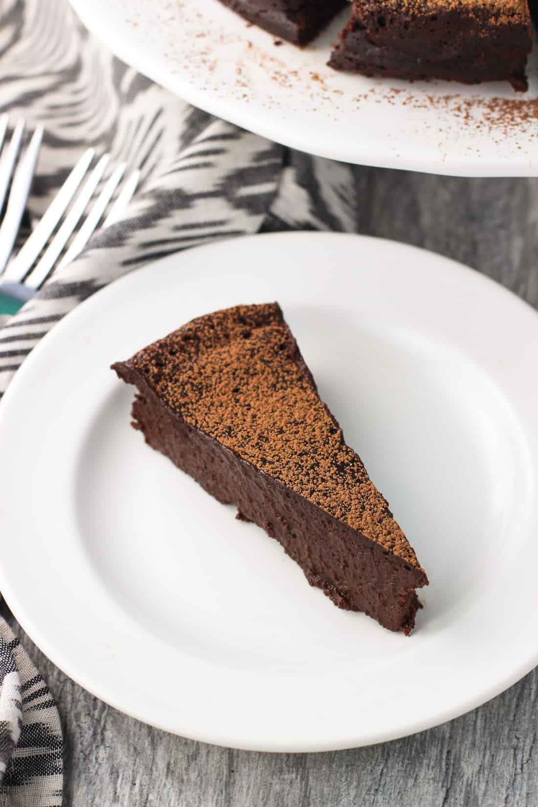 A side profile view of a fudgy chocolate cake slice on a dessert plate