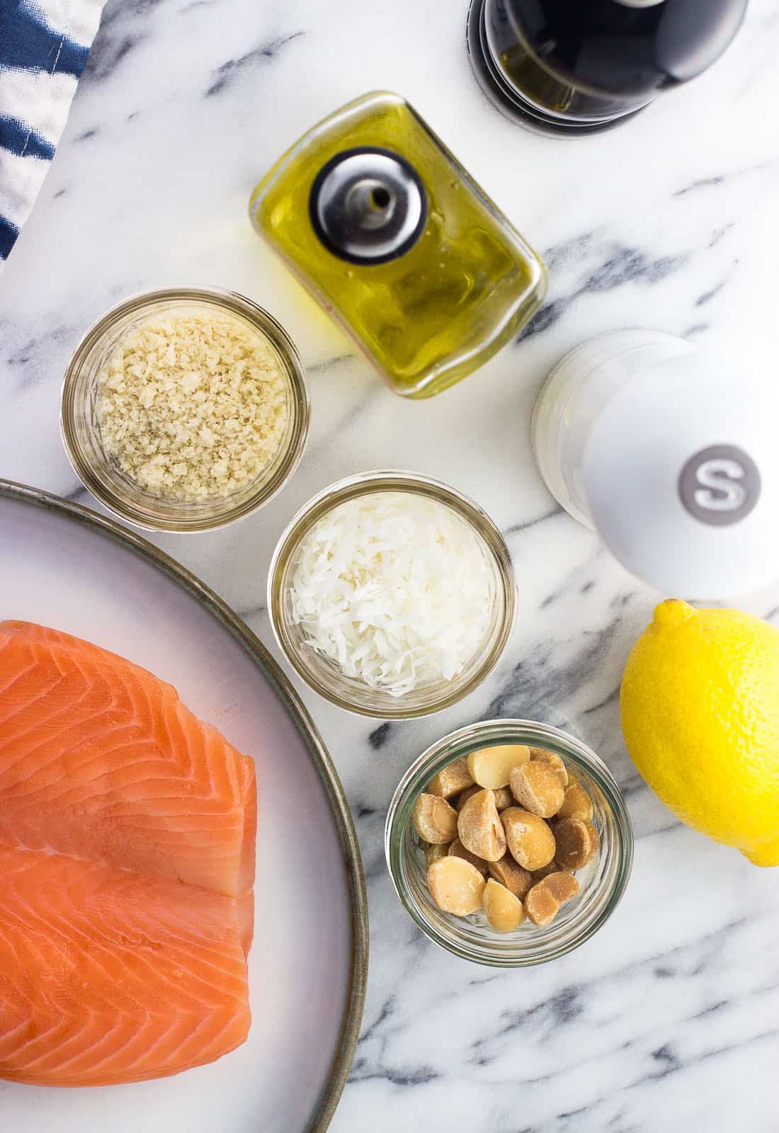 Salmon and the coating ingredients in separate containers on a marble board