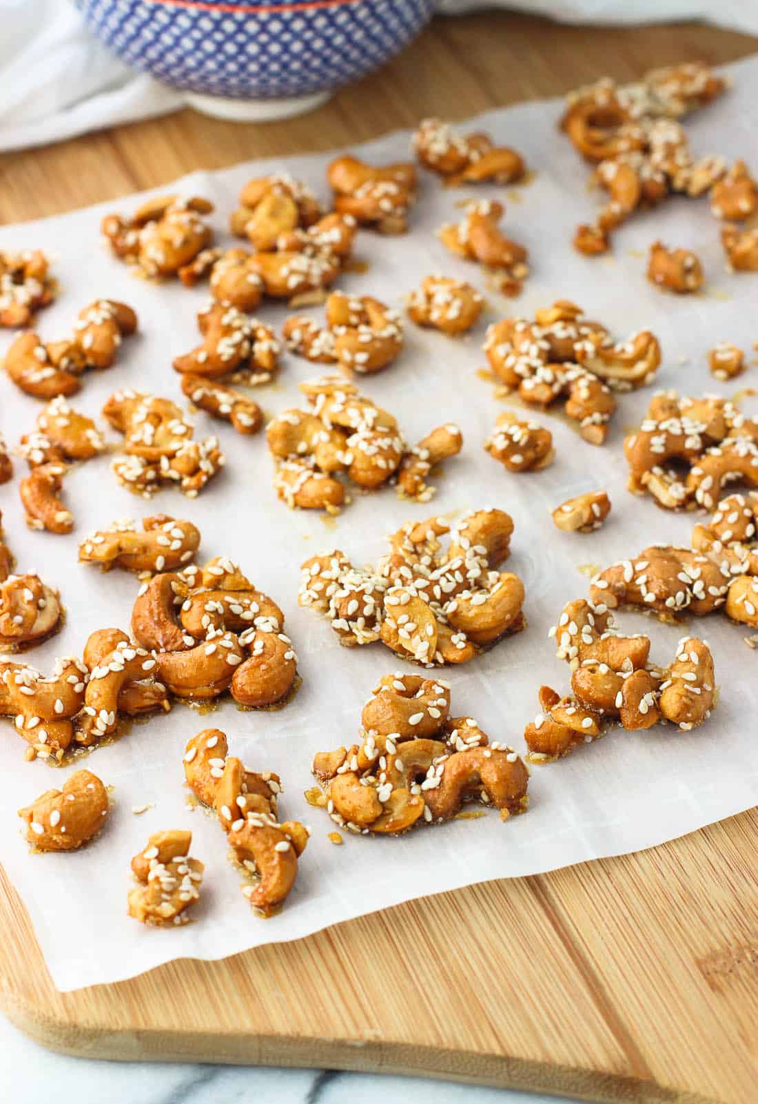 Cashew clusters on a sheet of parchment paper on a wooden board