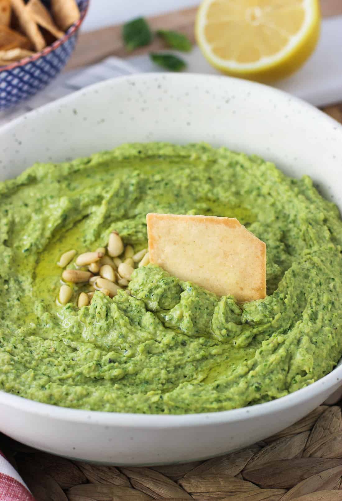 A pita chip dunked into a bowl of hummus ready to scoop