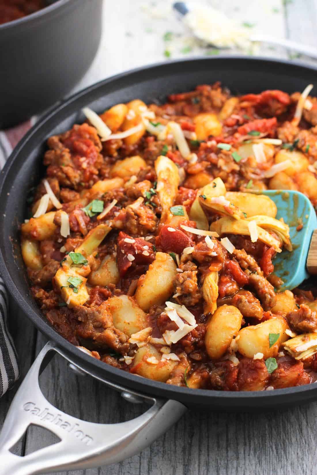 A skillet of gnocchi, sausage, and artichoke hearts covered in marinara sauce