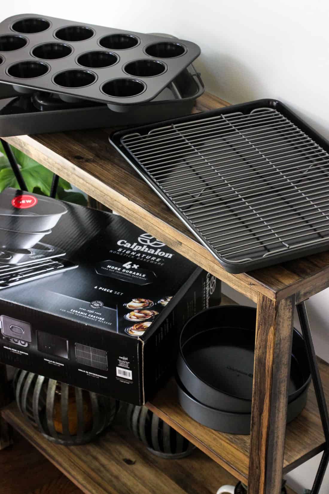 A Calphalon muffin tin, cooling rack, baking sheet, and cake pans on a wooden table