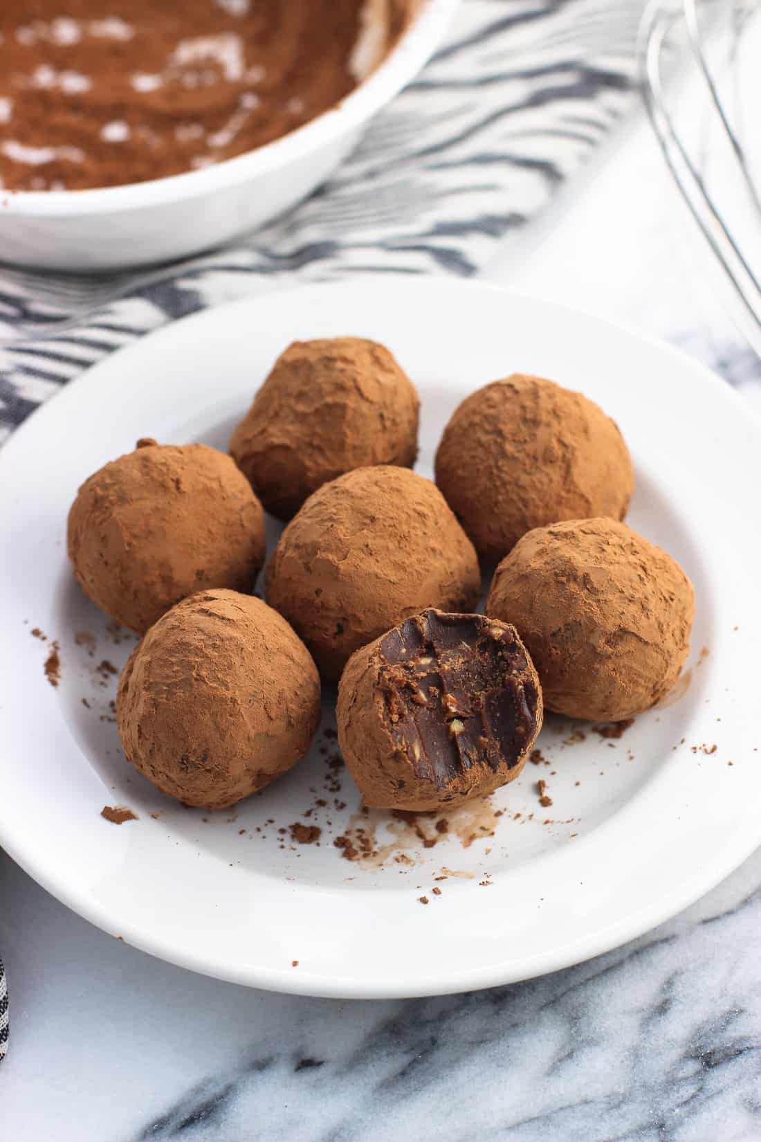 Peanut butter truffles on a small plate with a bite taken out of the front truffle.