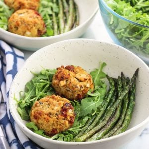 Plates of tuna cakes, arugula, and asparagus.