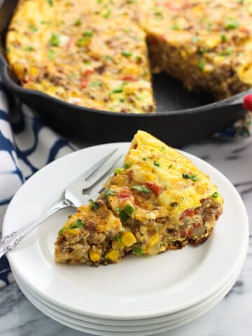 A slice of frittata on a plate in front of the pan.