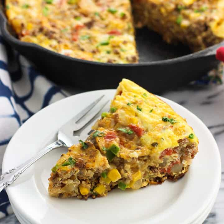 A slice of frittata on a plate in front of the pan.