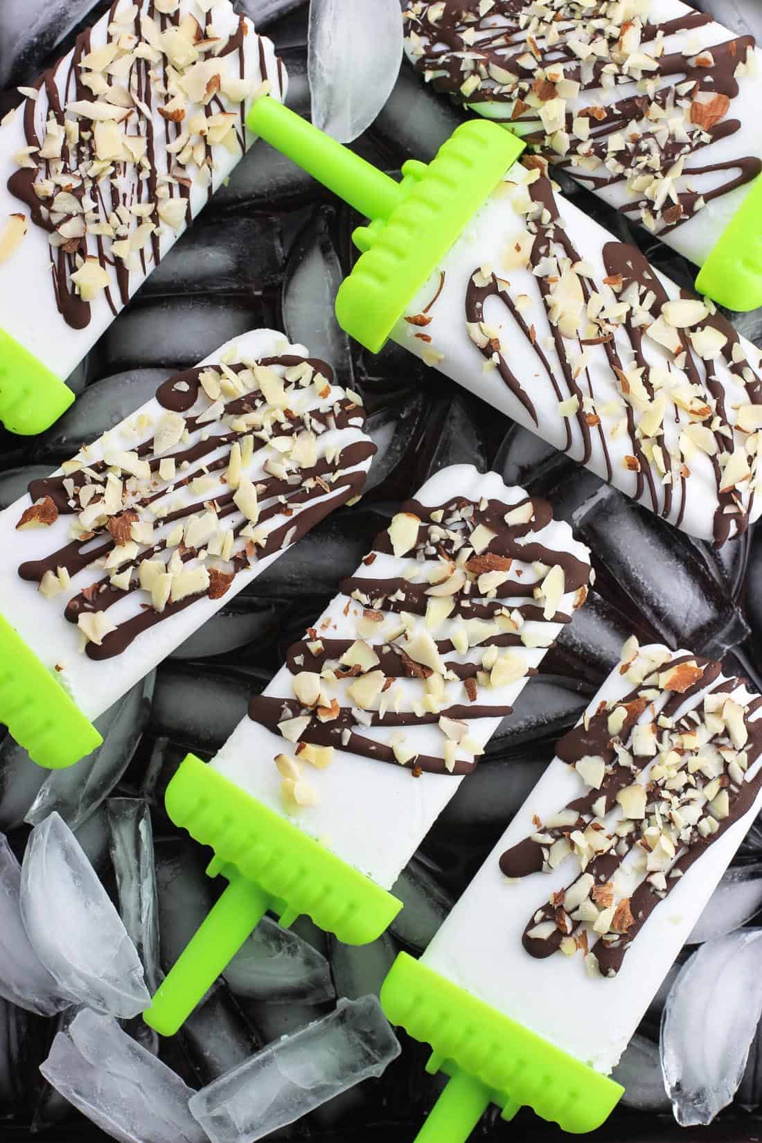 Coconut popsicles with plastic reusable popsicle holders laying on ice