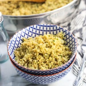 Cauliflower rice in a small bowl next to the pan and salt and pepper shakers.