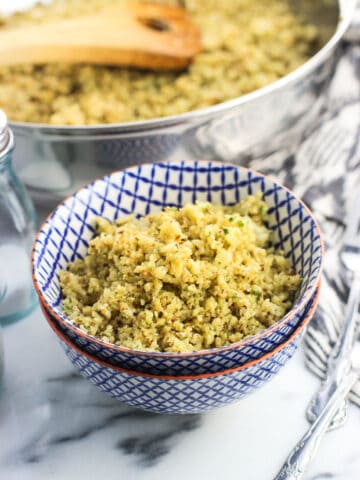 Cauliflower rice in a small bowl next to the pan and salt and pepper shakers.