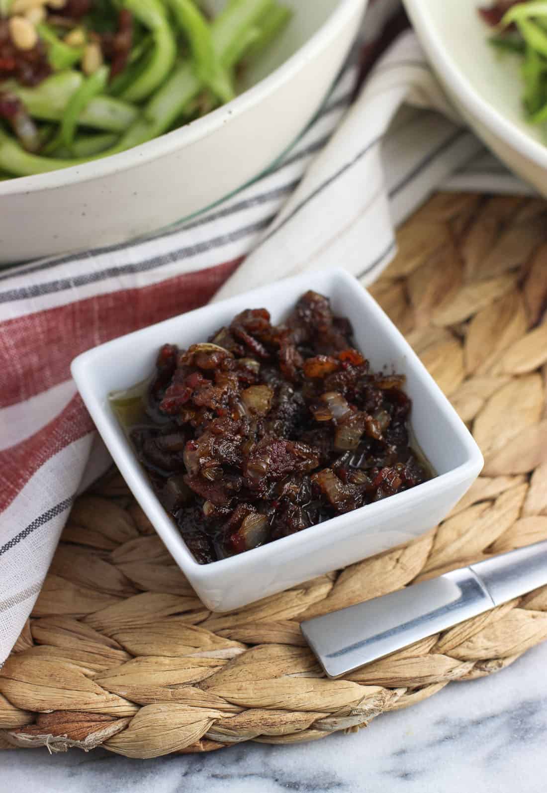 Warm bacon vinaigrette in a small ceramic dish