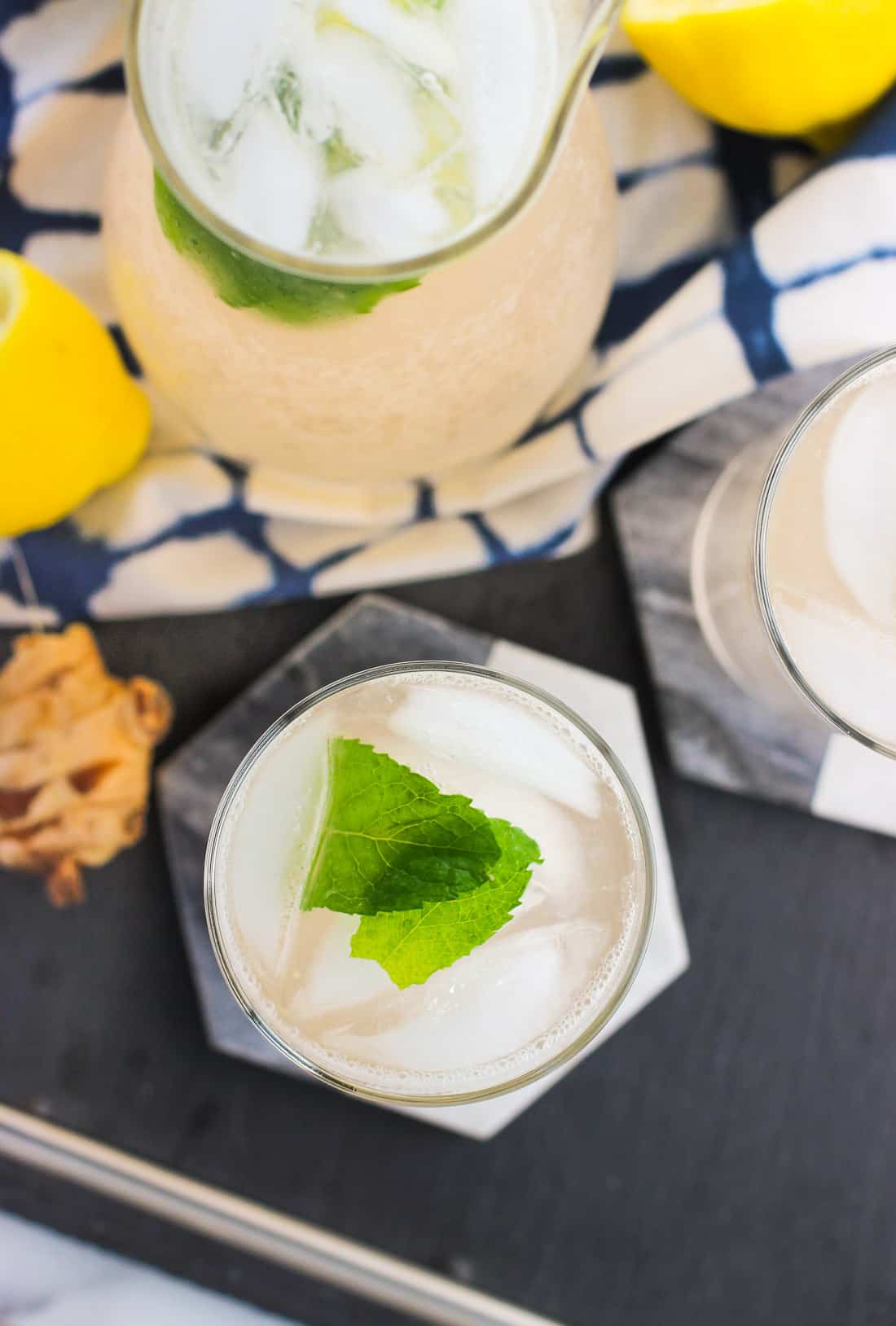 An overhead shot of two glasses of lemonade garnished with mint leaves and a larger carafe of lemonade