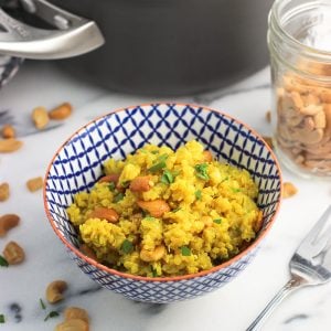 A bowl fo quinoa in front of the pan of it and various ingredients.