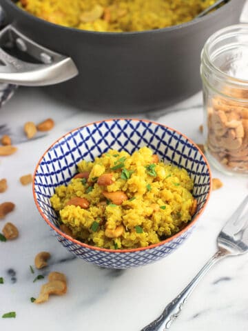 A bowl fo quinoa in front of the pan of it and various ingredients.