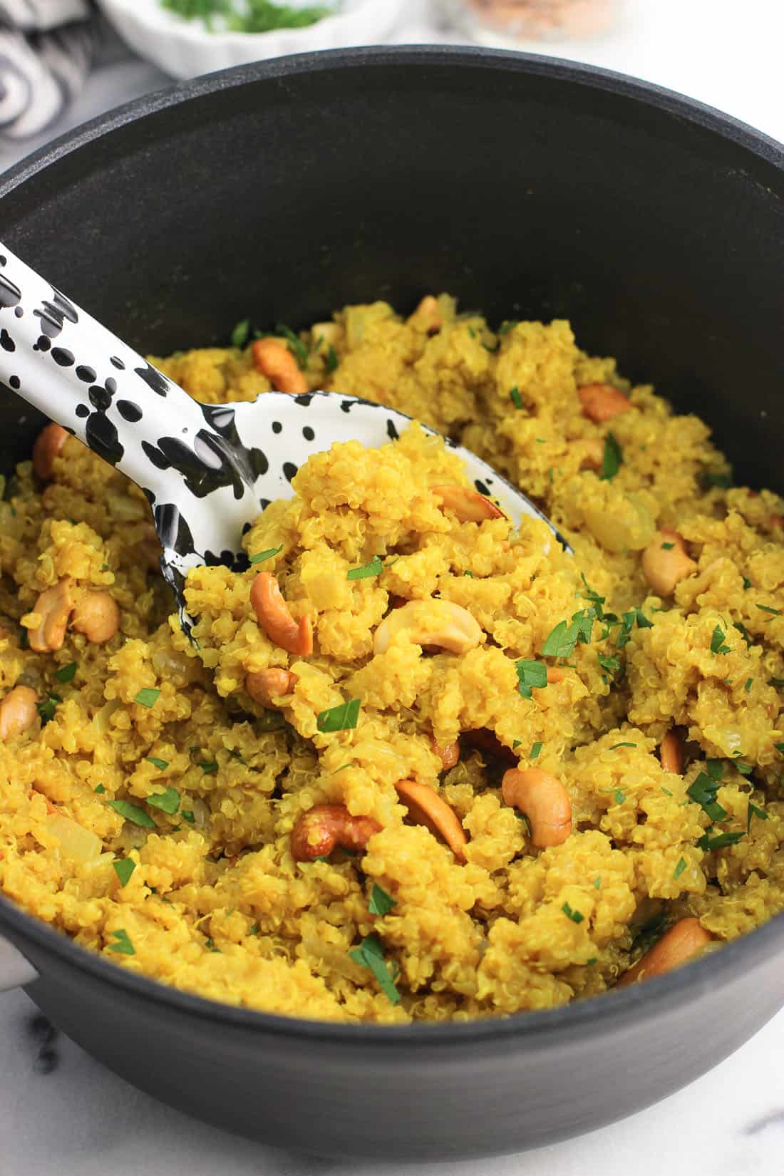 A serving spoon scooped into a pan of quinoa.