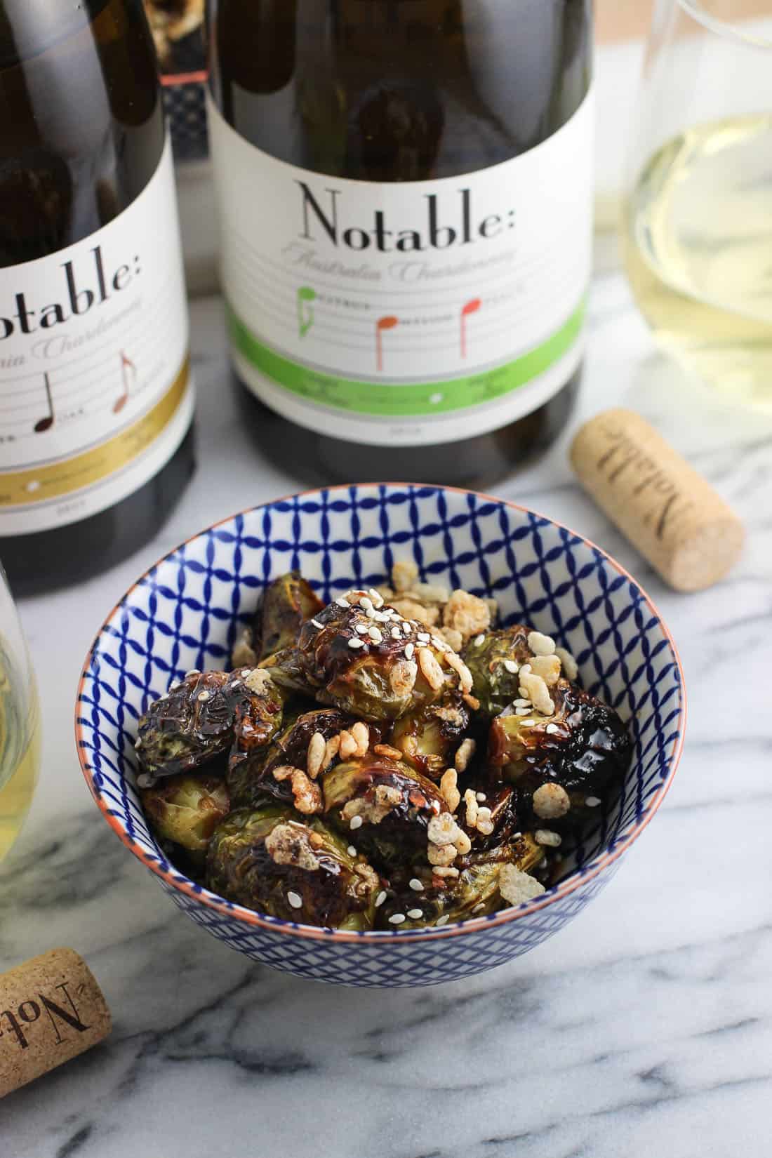 A small ceramic bowl of roasted Brussels sprouts covered in glaze with sesame seeds and puffed rice