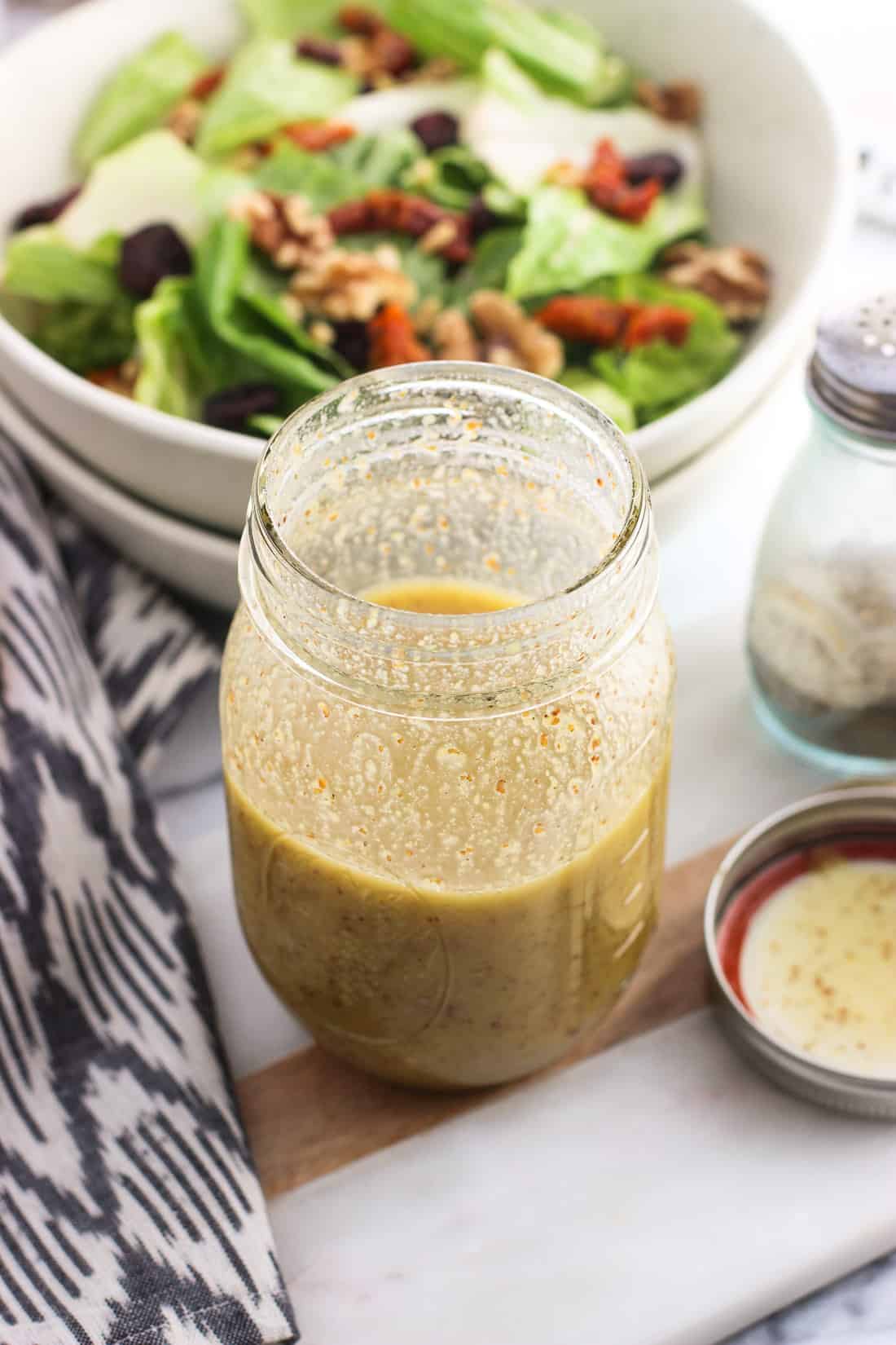 Shaken vinaigrette in a jar ready to be poured onto salad