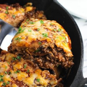 A wedge of beef tortilla pie being lifted by a spatula out of a cast iron pan to show the different layers