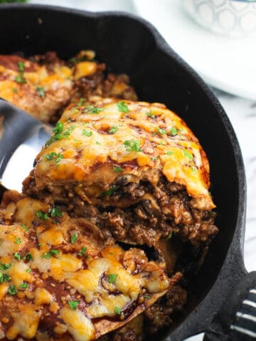 A wedge of beef tortilla pie being lifted by a spatula out of a cast iron pan to show the different layers