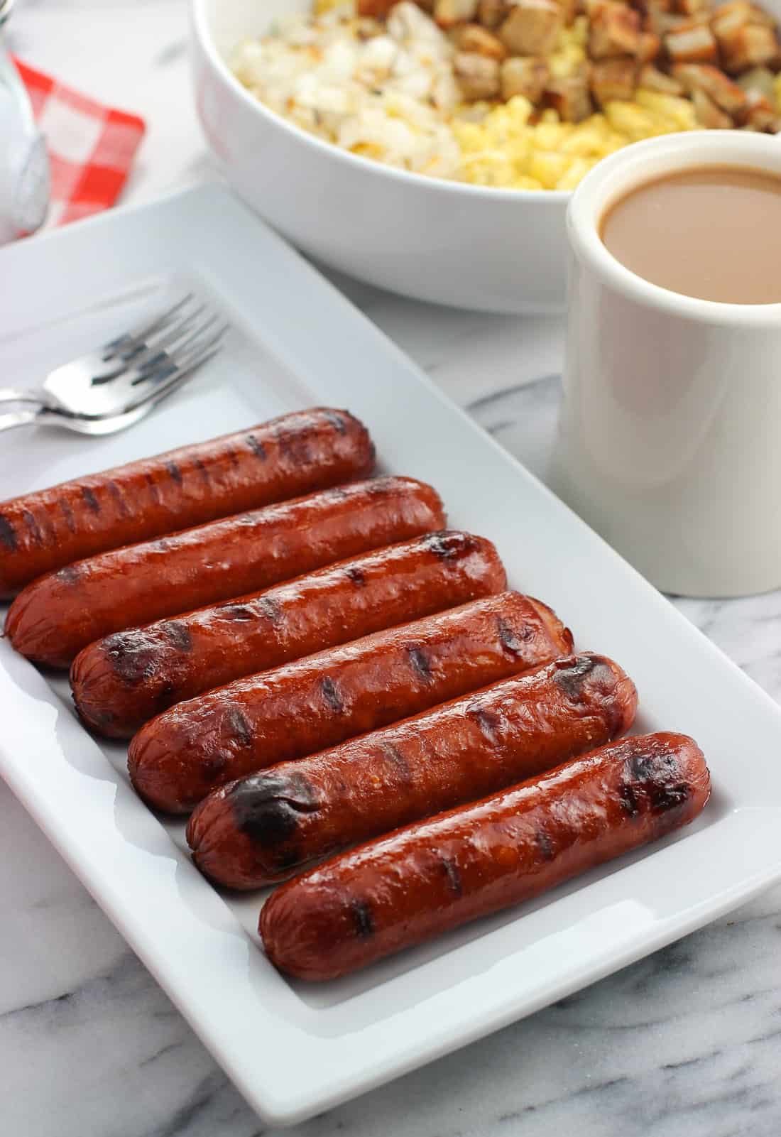 Six grilled smoked sausage links on a rectangular tray.